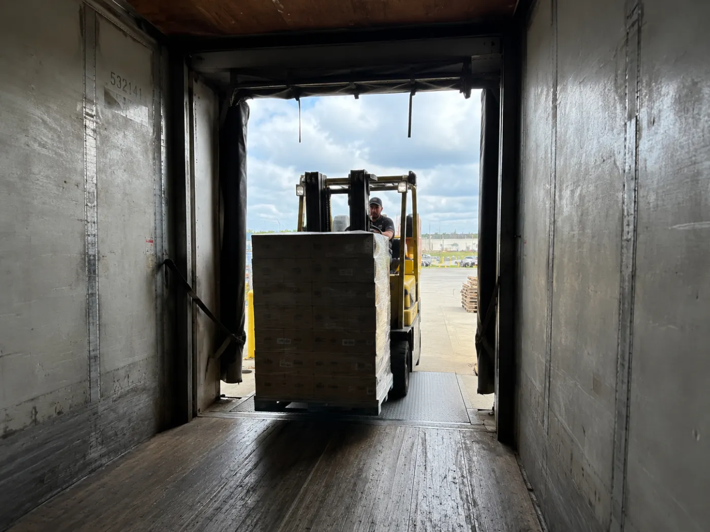 OnTrak crew transloading ocean-container cargo onto trucks at a cross-dock near a Florida port
